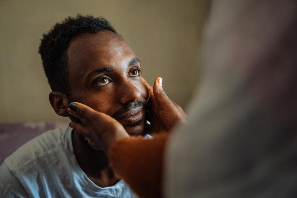 Dawit, a 26-year-old refugee who fled from Eritrea to Ethiopia six years ago, prepares to say goodbye to his mother before he departs for his new life in Canada. Photo: IOM 2023/Muse Mohammed 
 