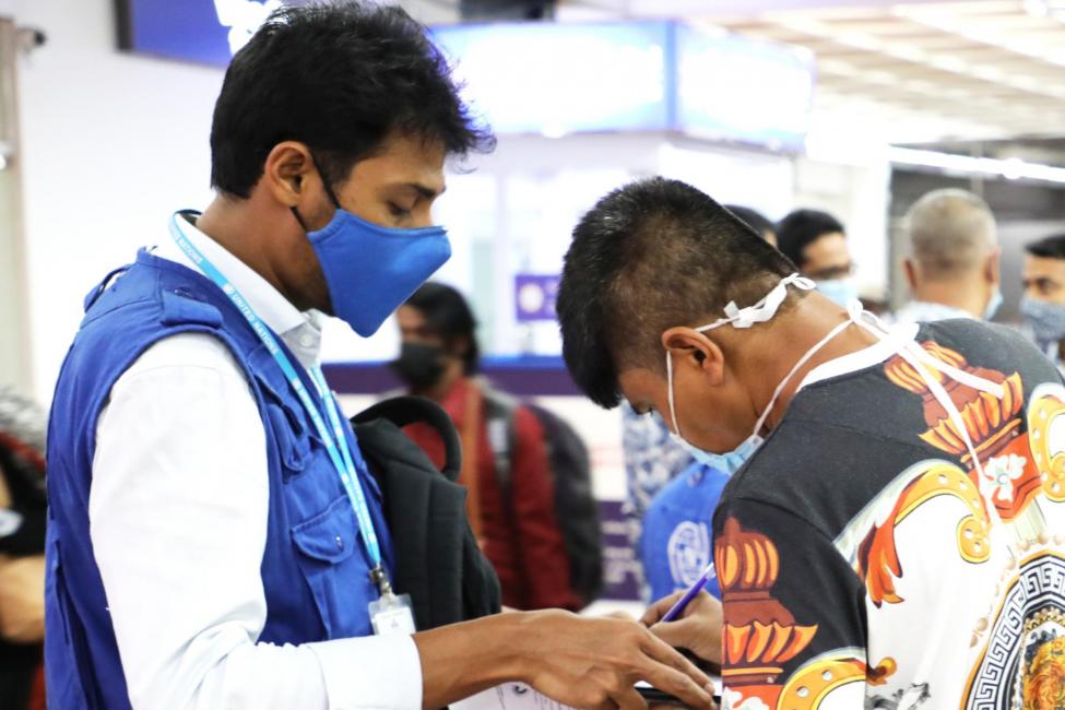 An IOM staff member in Dhaka advises a migrant about post-arrival reception assistance. Photo: IOM/Md. Al Amin Molla 