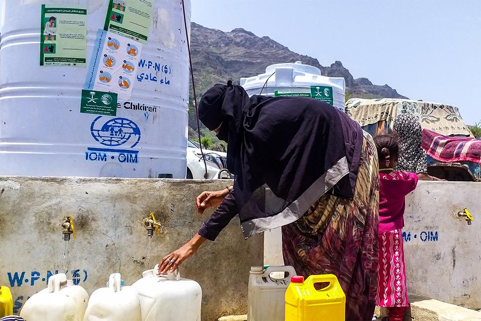 A woman fills jerrycans with clean drinking water at a displacement site in Ta’iz, Yemen.  Photo: Ayoob Zabl/IOM
