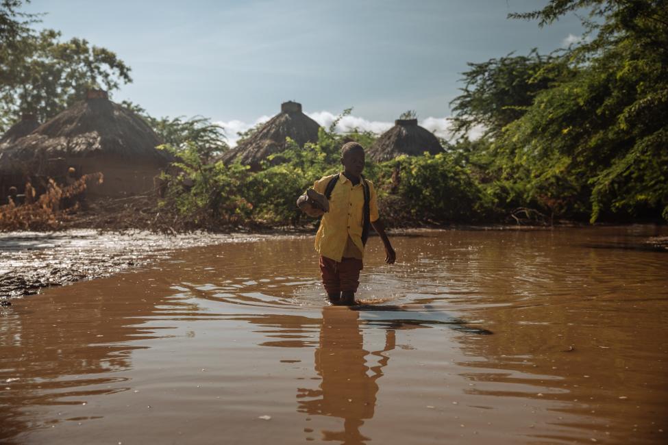 A young boy trudges through deep mud and river water on his way to school in Ethiopia. His village was flooded by heavy rains weeks ago. Photo: IOM 2018/ Mohammed Muse
