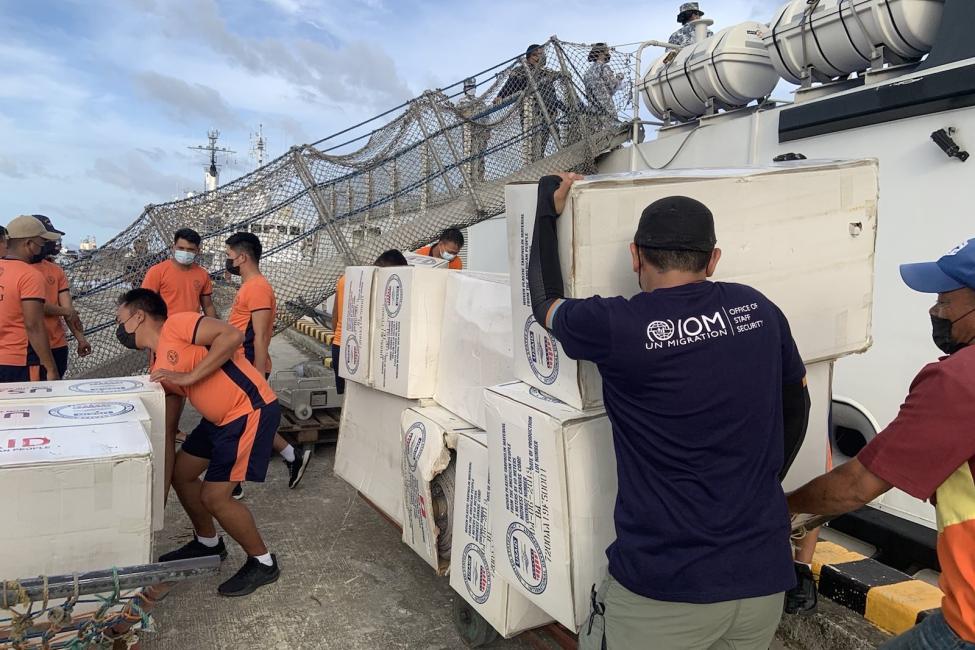 IOM staff and members of the Philippines Coast Guard unloading tarpaulins and other emergency supplies in Surigao City today, one of the areas the Category Five Typhoon Rai pounded with winds of up to 260kmh on Thursday (16 Dec). Photo: IOM 