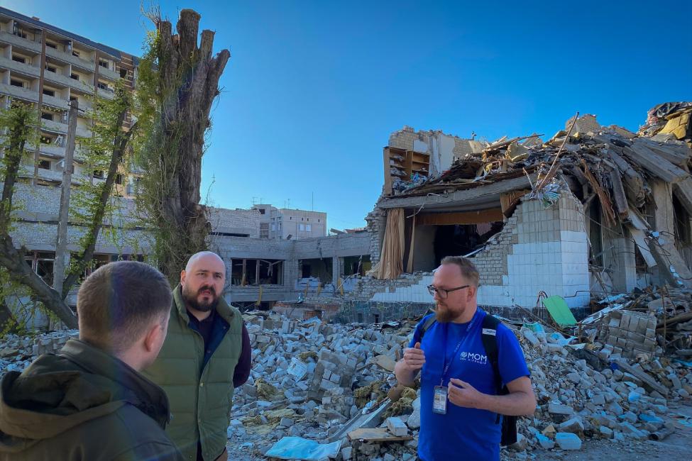 IOM staff and local authorities discussed the needs of internally displaced persons in front of a damaged school in Zhytomyr centre. Photo: IOM